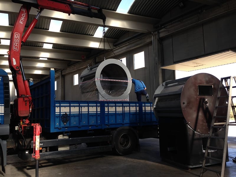 Coffee roaster part being lifted in an industrial hall with a crane
